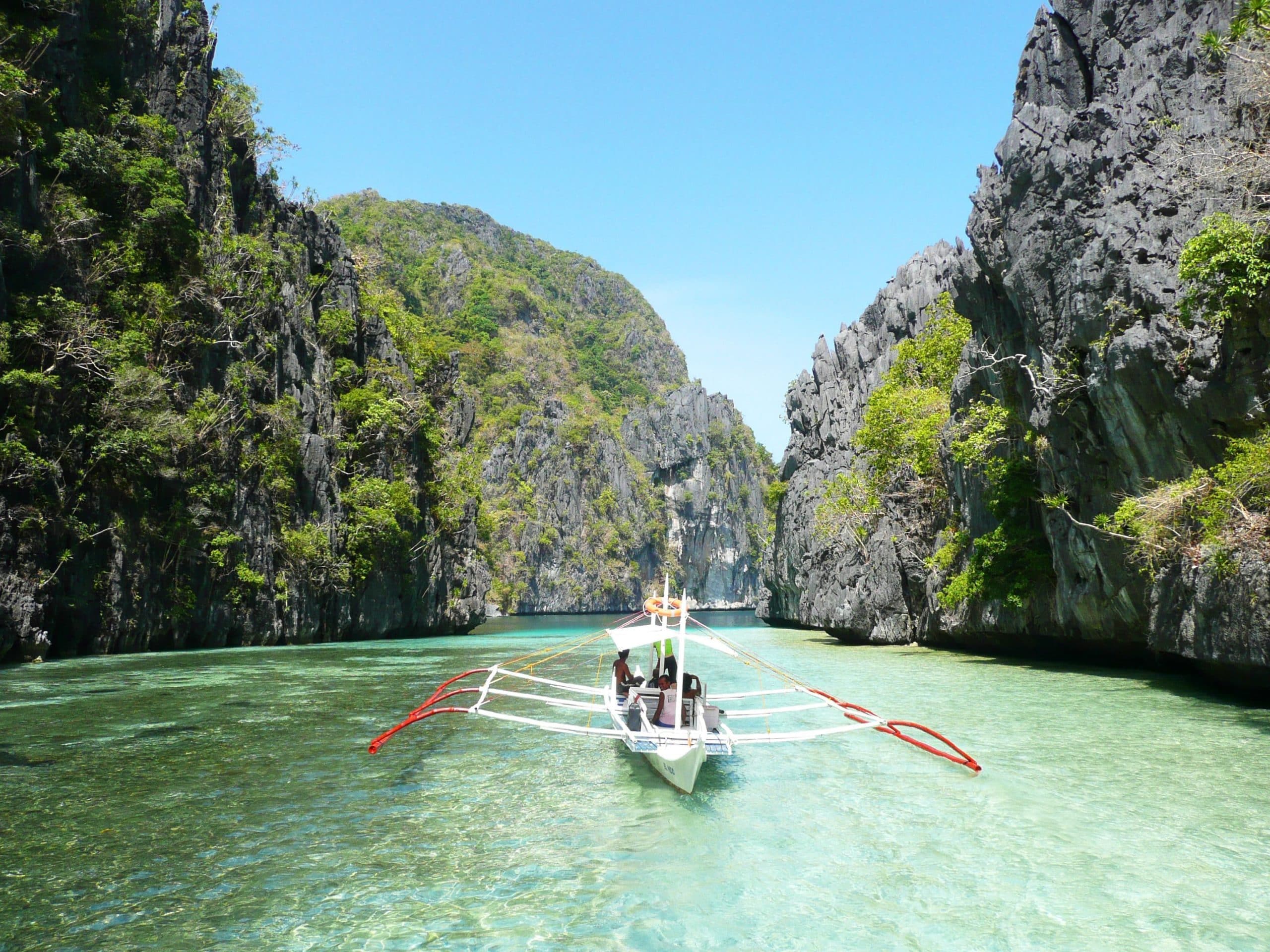 alt-text: boat in a lagoon between limestone hills